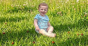 Annabelle joined the competition — help win amazing prizes! baby, child, daylight, field, grass, greenery, happy, ladybug, meadow, nature, outdoor, plants, portrait, short_sleeve_shirt, sitting, smile, summer, sunlight, toddler, wildflowers