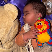 Kataleya a rejoint le concours — aidez-le/la à gagner de superbes lots ! baby, sleeping, crib, blanket, plush_toy, giraffe_toy, lion_toy, child, face, hand, furniture, cozy, cute, indoor, resting, infant, soft_toy, purple_blanket, brown_blanket, wooden_crib