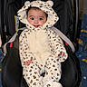 baby, child, infant, onesie, leopard_print, hood, ears, car_seat, seatbelt, smiling, tongue_out, cute, plush, clothing, indoors, person, portrait, happy, cozy, colorful_background