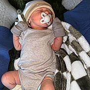 Jack is registered to the contest to win money with this photo: baby, newborn, pacifier, mittens, hat, blanket, socks, legs, sleeping, infant, clothing, cozy, soft, person, rest, comfort, cute, indoor, portrait, relaxation