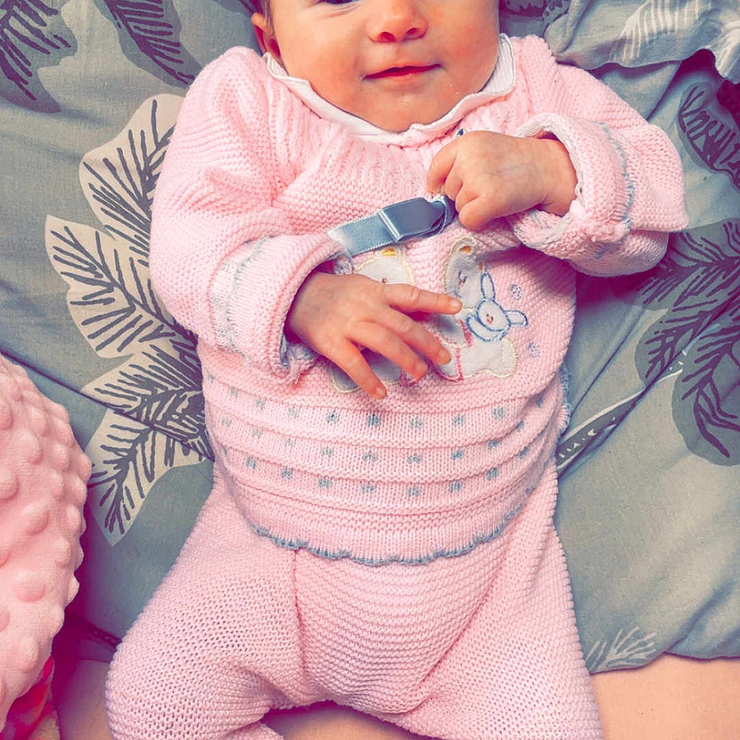 Esmée Cousantien participe au concours pour gagner de l'argent avec cette photo : baby, blanket, child, comfort, cozy, cute, face, hand, happy, indoors, infant, knitted_outfit, lying_down, pillow, pink_clothing, portrait, relaxing, smiling, soft_texture, toddler