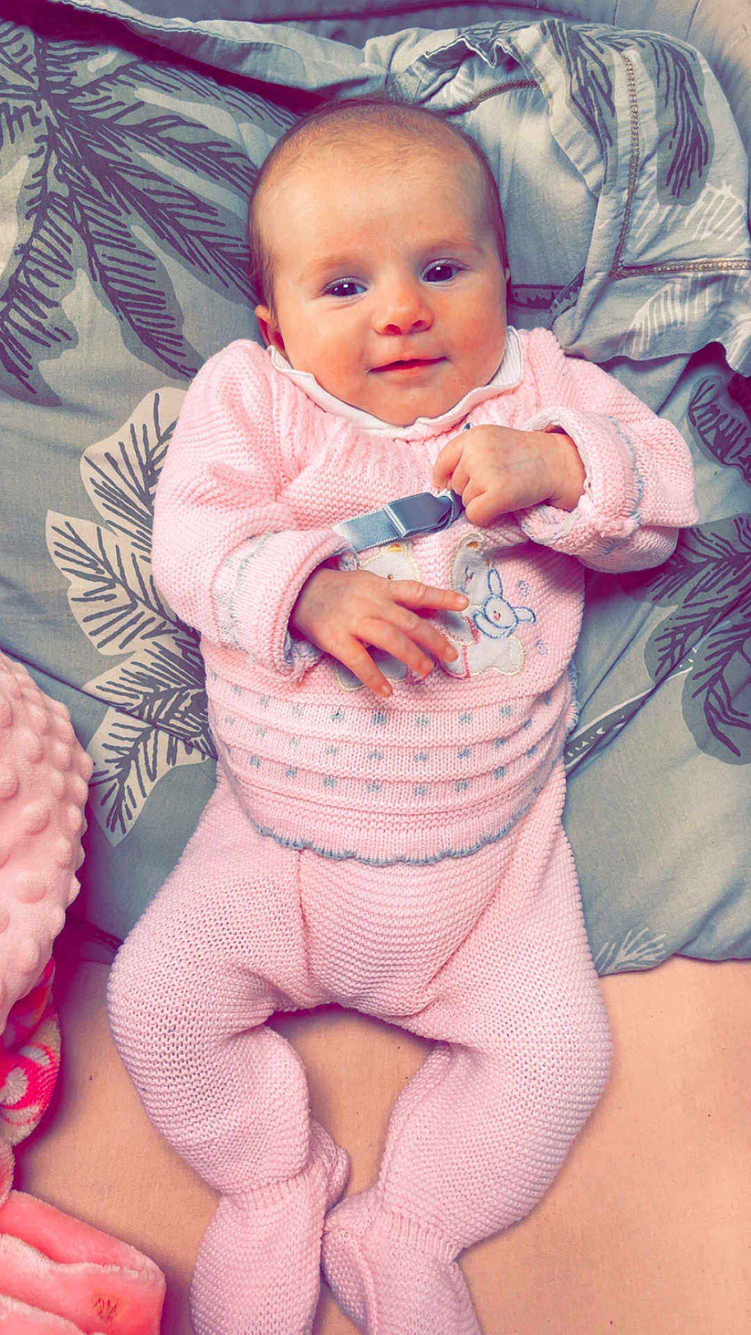 Esmée Cousantien participe au concours pour gagner de l'argent avec cette photo : baby, infant, pink_clothing, knitted_outfit, smiling, cute, lying_down, pillow, blanket, soft_texture, hand, face, happy, child, cozy, indoors, comfort, toddler, portrait, relaxing