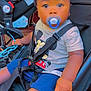 toddler, child, pacifier, stroller, cap, mickey_mouse, shirt, shorts, seatbelt, hand, face, sitting, blue, toy, baby, infant, young_child, cute, outdoor, baby_clothing