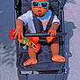 Lucas-Joao Zayn participe au concours pour gagner de l'argent avec cette photo : baby, child, stroller, sunglasses, toy, orange_shorts, white_shirt, barefoot, outdoor, sunny, road, shadow, black_stroller, seatbelt, cute, person, playing, summer, casual, happy