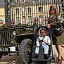 Lucas-Joao Zayn a rejoint le concours — aidez-le/la à gagner de superbes lots ! building, child, flags, gate, glasses, historic, hoodie, military_uniform, outdoor, pavement, person, portrait, shoes, stroller, sunny, toddler, vehicle, vintage_jeep, wheel, woman