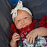 baby, infant, child, stroller, portrait, face, blue_eyes, headband, bow, red_clothing, floral_pattern, sitting, harness, seatbelt, indoor, closeup, serious_expression, hands, fabric, photography