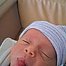 Liam joined the competition — help win amazing prizes! newborn, baby, infant, face, hat, striped_hat, tongue_out, close_up, skin, person, cute, hospital, sleepy, expression, child, headwear, indoors, soft_light, blanket, cozy