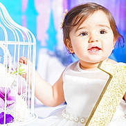 Elaynne joined the competition — help win amazing prizes! baby, child, girl, white_dress, pearls, glitter, number_one, flower, purple_flower, birdcage, decor, portrait, smiling, happy, celebration, indoor, cute, face, hands, bright