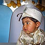 Tao participe au concours pour gagner de l'argent avec cette photo : child, toddler, traditional_clothing, hat, feather, face, portrait, balloons, celebration, festive, party, costume, curious, young_child, indoors, decorations, event, cute, fashion, person