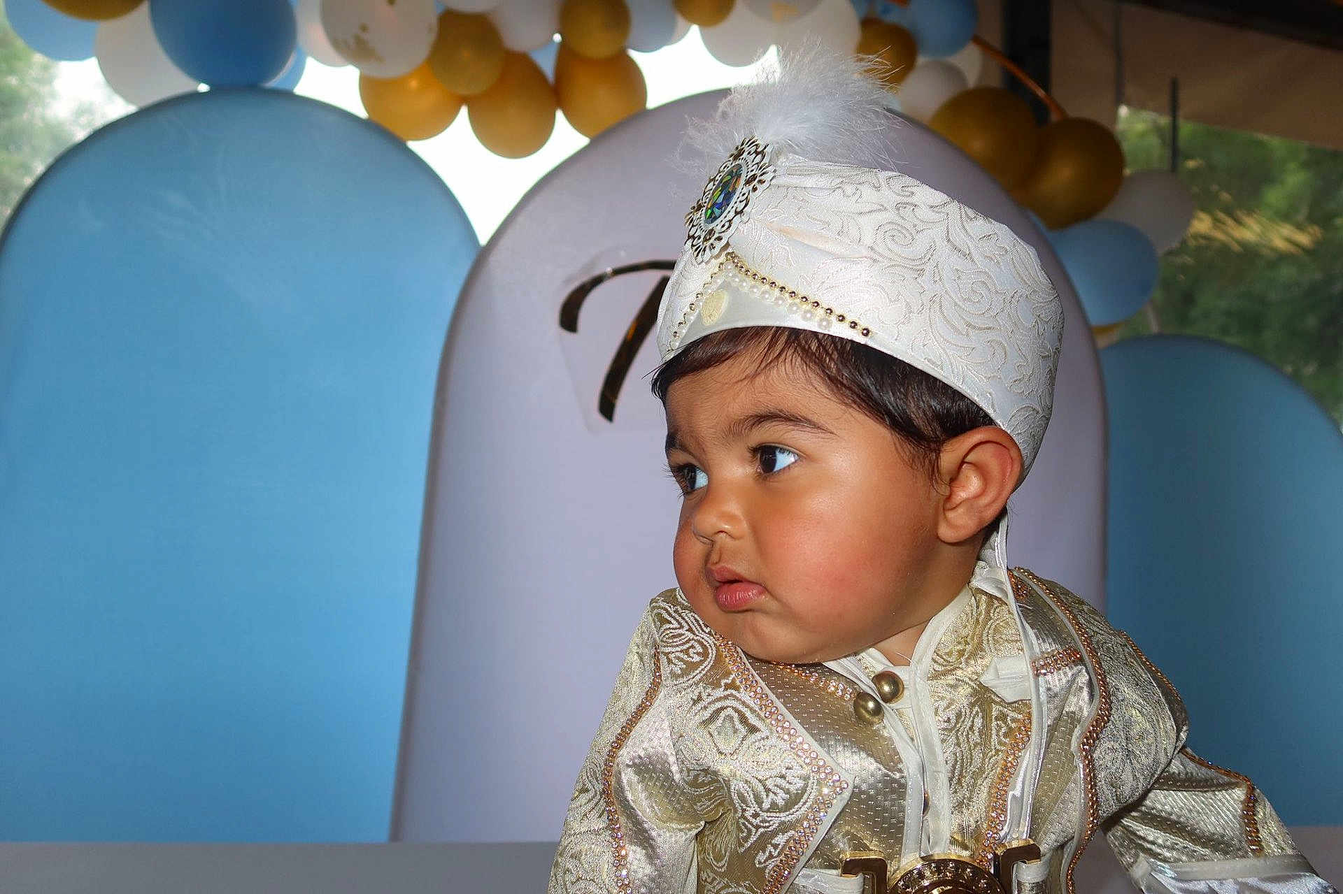 Tao participe au concours pour gagner de l'argent avec cette photo : child, toddler, traditional_clothing, hat, feather, face, portrait, balloons, celebration, festive, party, costume, curious, young_child, indoors, decorations, event, cute, fashion, person