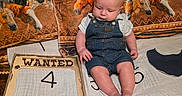 Asstro is registered to the contest to win money with this photo: baby, bare_feet, bed, blanket, child, denim, fabric, family_photo, horse, horses, indoor, infant, milestone_photo, number_four, overalls, portrait, sitting, text, wanted_poster, western_theme