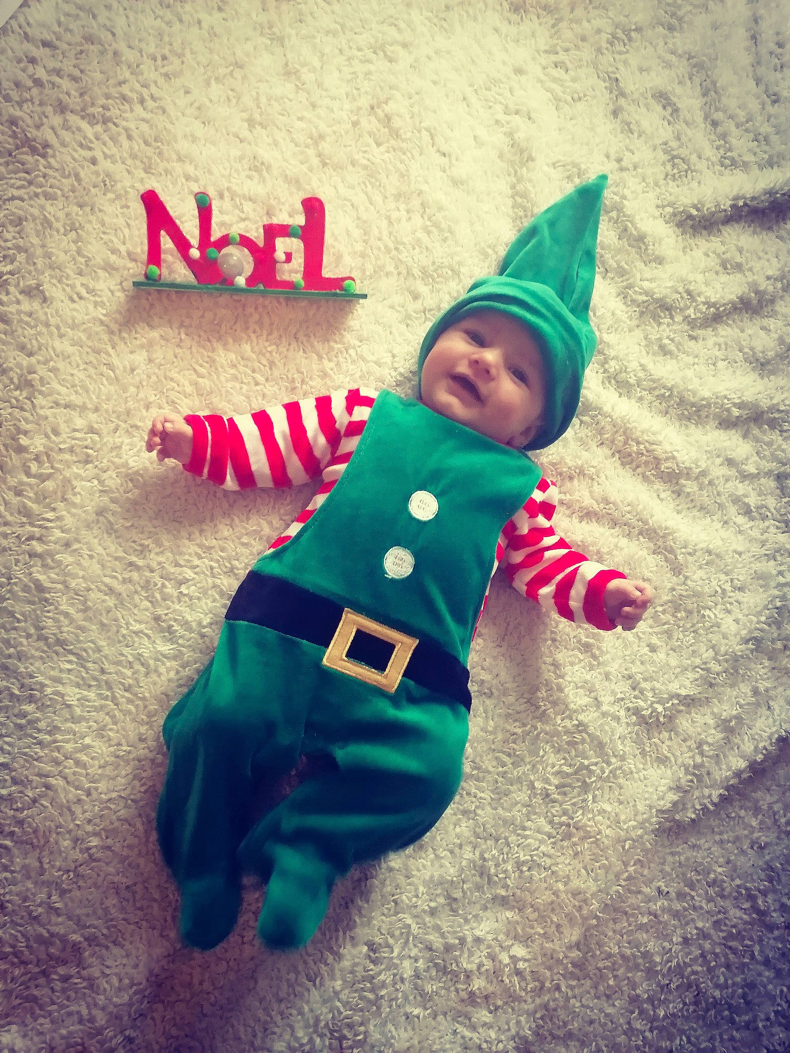 Adam participe au concours pour gagner de l'argent avec cette photo : baby, baby_toddler_clothing, child, christmas, christmas_eve, costume, costume_accessory, costume_hat, fictional_character, flag, green, headwear, holiday, person, play, toddler, winter