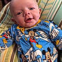 baby, infant, mickey_mouse, onesie, clothing, pillow, striped_pillow, blue, yellow, red, smile, face, head, person, cute, indoor, child, young, happy, lying_down