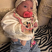 Lynaïa a rejoint le concours — aidez-le/la à gagner de superbes lots ! baby, infant, pacifier, headband, bow, clothing, bib, jeans, patterned_blanket, pillows, zebra_print, indoor, cute, child, small_hands, sitting, soft_lighting, portrait, cozy, comfortable