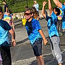 Malaki is registered to the contest to win money with this photo: active, adult, background, blue_shirt, casual_clothing, child, children, fun, greenery, group, outdoor, pavement, people, play, recreation, smile, sunglasses, sunlight, tie_dye_shirt, water_balloon