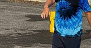 Malaki joined the competition — help win amazing prizes! active, bandage, boy, casual_clothing, child, concrete_wall, daytime, greenery, outdoor, pavement, playful, shadow, short_hair, shorts, smile, summer, sunglasses, sunlight, tie_dye_shirt, yellow_bucket