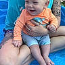 baby, child, tattoo, blue_pool, orange_shirt, shorts, smiling, adult, hand, legs, outdoor, water, summer, person, skin, cute, happy, holding, sitting, play