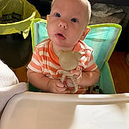Castiel is registered to the contest to win money with this photo: baby, child, clothing, curious, expression, eyes, face, furniture, hand, head, high_chair, indoor, infant, mouth, person, seat, skin, striped_shirt, teddy_bear, toy