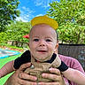 Jax is registered to the contest to win money with this photo: accessories, baby, bodypart, cap, clothing, face, finger, grass, hat, head, nature, outdoors, pants, park, person, photography, plant, portrait, pottedplant, tree