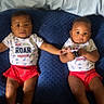 baby, infant, twin, matching_clothes, red_shorts, blue_cushion, holding_hands, cute, indoor, portrait, child, smiling, socks, short_sleeve, lying_down, two_children, people, young, happy, casual