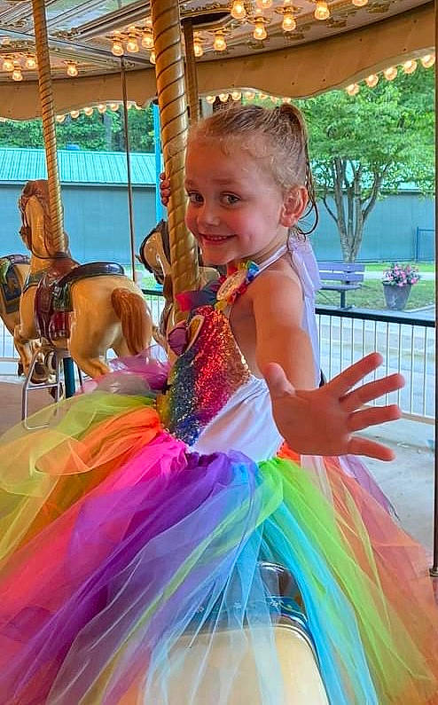 Ember is registered to the contest to win money with this photo: ballet_tutu, carousel, child, entertainment, event, fun, happy, joy, leisure, magenta, mythical_creature, party, performing_arts, person, pink, plant, pole, public_event, recreation, smile