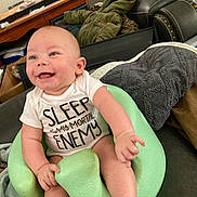 Axl joined the competition — help win amazing prizes! baby, infant, smile, onesie, text_on_shirt, green_baby_seat, foam_seat, legs, hand, blue_eyes, couch, blanket, living_room, furniture, happy, portrait, skin, chubby, cute, sitting
