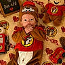 baby, infant, child, portrait, lying_down, smiling, wide_eyed, costume, beaver_costume, red_shirt, plush_toy, stuffed_animal, blanket, heart_pattern, toy_truck, welcome_sign, indoor, themed_setup, buc_ee's, cozy