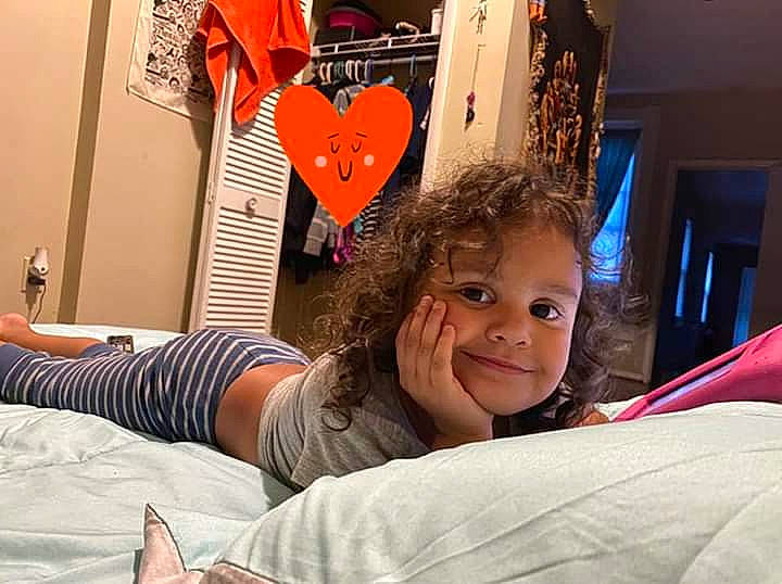 Lavinia is registered to the contest to win money with this photo: art, bed, child, comfort, elbow, finger, flooring, fun, happy, human_leg, joy, leisure, linens, person, room, sitting, smile, t_shirt, toddler, tree