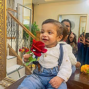 Gursher Singh is registered to the contest to win money with this photo: toddler, child, rose, flower, mirror, reflection, stairs, suspenders, jeans, white_shirt, smile, indoor, wooden_surface, decor, adult, thumbs_up, happy, casual_clothing, person, portrait