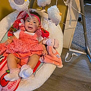 Yaretzy is registered to the contest to win money with this photo: baby, infant, baby_swing, plush_toy, stuffed_animal, headband, pink_clothing, white_socks, flooring, wood_floor, baby_blanket, toy_sheep, indoor, child, happy, cute, seated, soft_toys, home, playtime