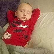 Myi-Khel is registered to the contest to win money with this photo: child, sleeping, bed, pillow, blanket, quilt, red_shirt, dinosaur, indoors, cozy, resting, peaceful, young, toddler, portrait, person, clothing, head, face, relaxation