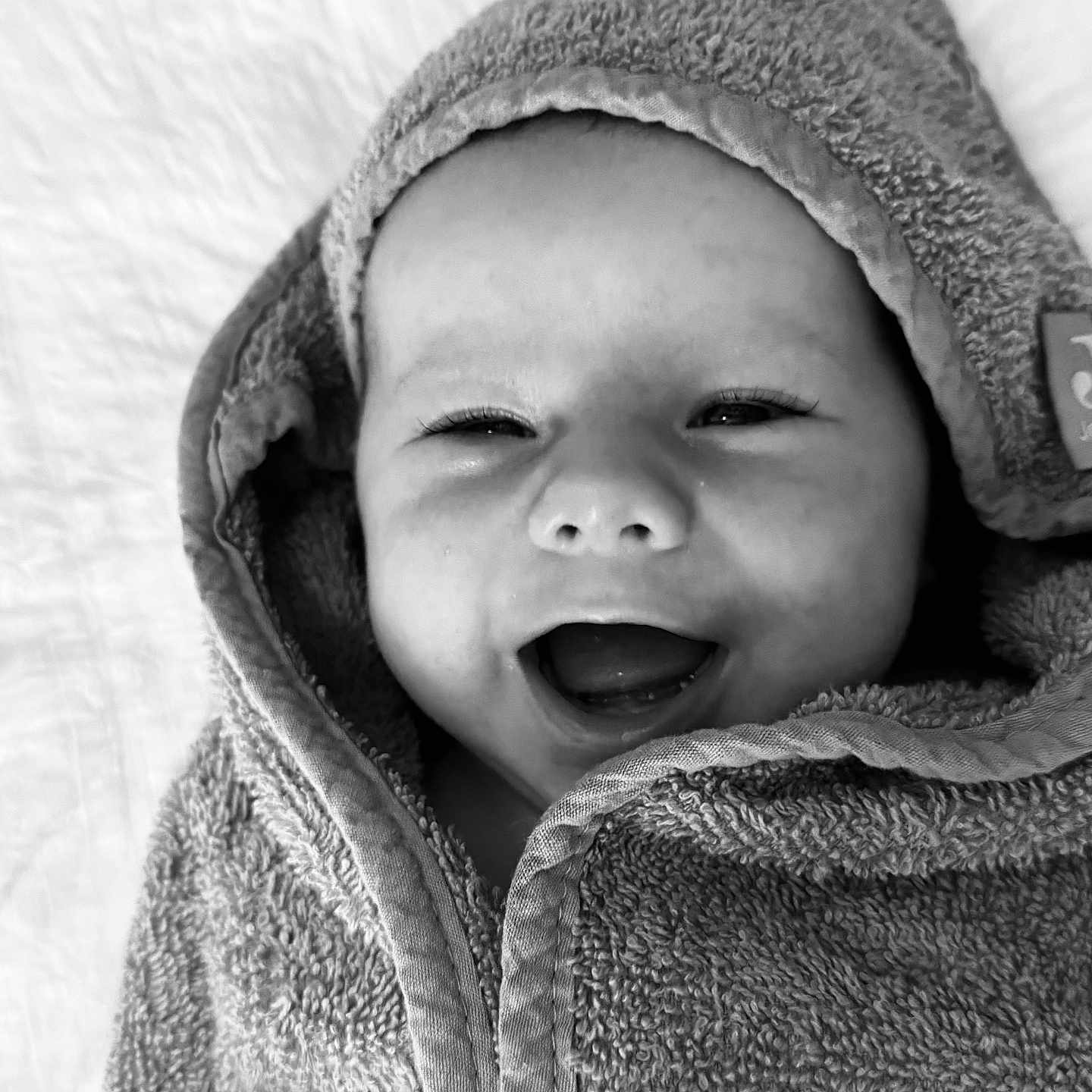 Léo a rejoint le concours — aidez-le/la à gagner de superbes lots ! baby, black_and_white, blanket, child, closeup, cute, expression, eyes, face, happy, hooded_towel, infant, laying_down, mouth, portrait, skin, smiling, soft_texture, towel, wrapped