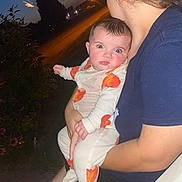 Evelyn is registered to the contest to win money with this photo: baby, child, person, adult, night, outdoor, firework, pajamas, holding, curious, surprised, face, arm, shoulder, plant, flower, grass, chair, dark, twilight