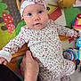 baby, child, infant, headband, blue_eyes, floral_pattern, hand, play_mat, toy, colorful, person, clothing, sleeves, cute, indoor, looking_at_camera, skin, face, lying_down, supportive_hand