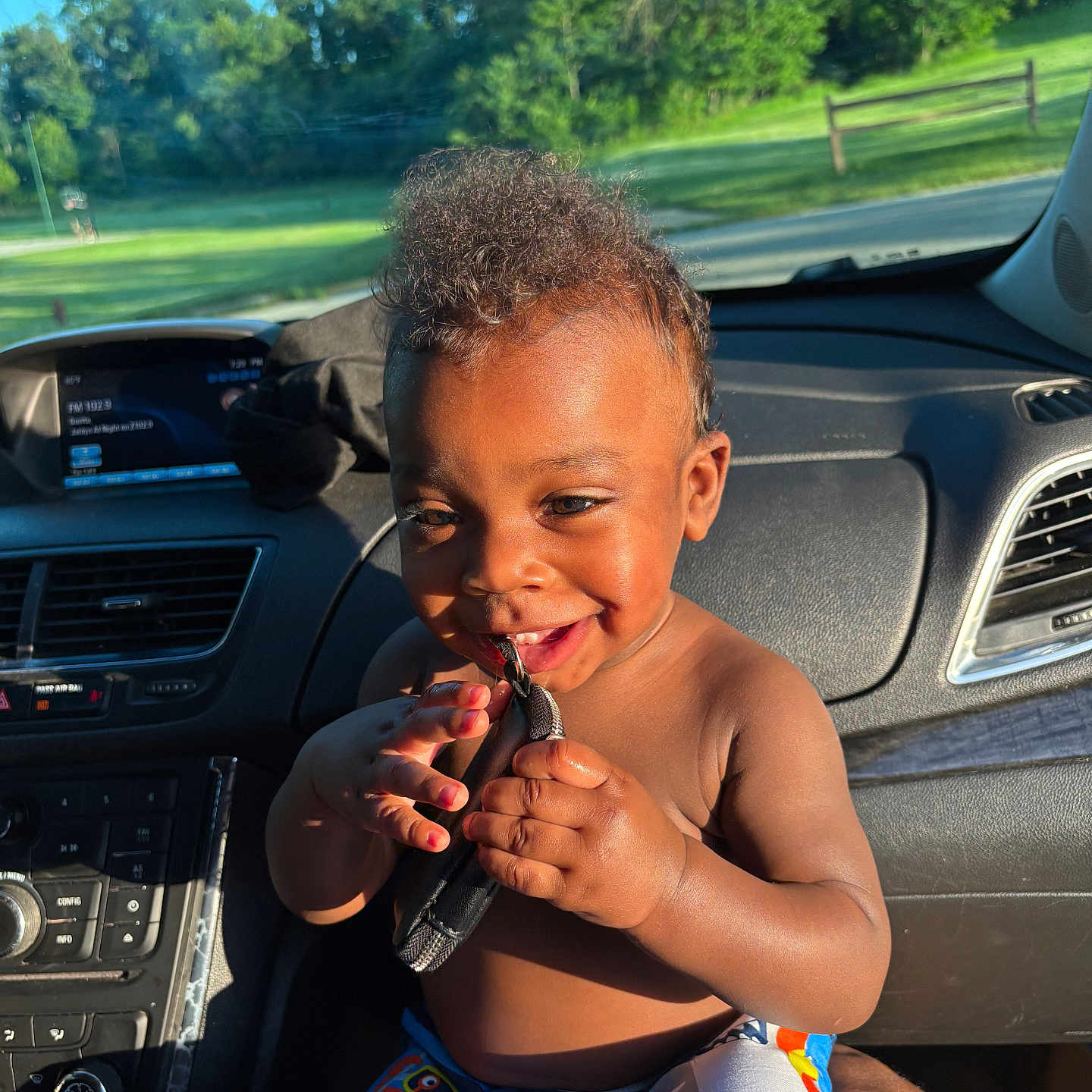 Kaysyn is registered to the contest to win money with this photo: blue_shorts, car_interior, child, crab_pattern, dashboard, daylight, face, greenery, hands, happy, person, playful, seat, shorts, skin, smiling, sunlight, toddler, trees, window