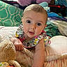 baby, infant, child, face, eyes, arm, blanket, plush_toy, cushion, bed, clothing, patterned, indoor, cute, expression, soft, colorful, toy, person, portrait