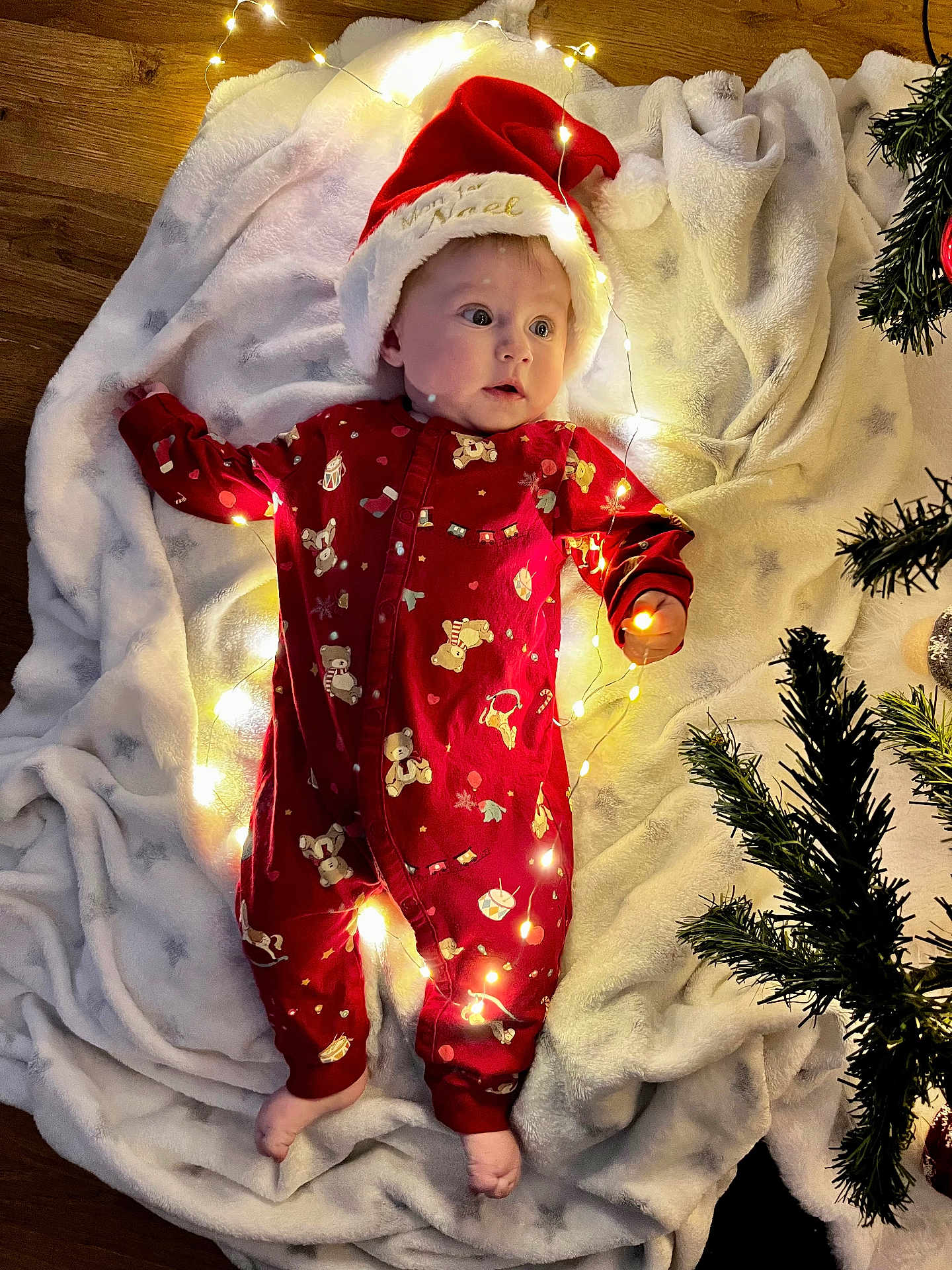 Camelia a rejoint le concours — aidez-le/la à gagner de superbes lots ! baby, christmas, holiday, santa_hat, pajamas, blanket, lights, decorations, floor, infant, cute, festive, cozy, tree, footwear_free, indoors, celebration, red_clothing, toddler, smiling