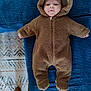 baby, child, onesie, brown, fuzzy, hood, face, couch, blue, texture, footwear, boots, carpet, pattern, indoor, infant, cute, cozy, clothing, portrait