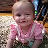 Jocelyn joined the competition — help win amazing prizes! baby, child, smiling, pink_clothing, bow, carpet, crawling, indoor, wooden_furniture, face, happy, person, cute, young_child, home, floor, hands, head, infant, toddler