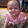baby, child, smiling, pink_clothing, bow, carpet, crawling, indoor, wooden_furniture, face, happy, person, cute, young_child, home, floor, hands, head, infant, toddler