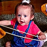 toddler, child, indoor, tiara, pink_shirt, blue_overalls, rope, carpet, wooden_floor, playful, cute, person, young_child, smiling, sitting, toy, happy, curious, bright_colors, casual_clothing