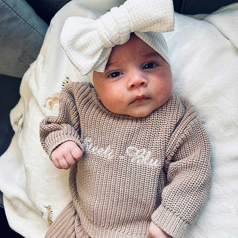 Steeli-Blu joined the competition — help win amazing prizes! baby, blanket, bonnet, cap, clothing, face, happy, hat, head, hood, knitwear, newborn, person, photography, portrait, sitting, sleeve, smile, sweater