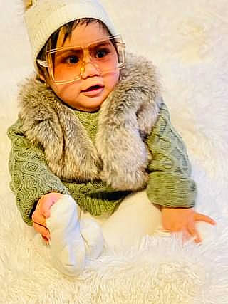 Natalie is registered to the contest to win money with this photo: animal_product, baby, cheek, child, comfort, eye, fashion_accessory, fur, fur_clothing, gesture, happy, headgear, headwear, hood, jacket, linens, natural_material, person, sitting, sleeve