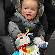 Christopher is registered to the contest to win money with this photo: baby, child, car_seat, winter_jacket, fur_hood, plush_toy, zebra_toy, smiling, happy, infant, seatbelt, car_interior, cute, cozy, warm_clothing, child_safety, toy, hand, face, indoor