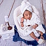 newborn, baby, sleeping, white_robe, towel_turban, basket, cushion, blue_rug, floor, miniature_lamp, rotary_phone, small_table, indoor, cozy, cute, peaceful, infant, soft_texture, relaxing, portrait