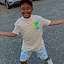 child, boy, smiling, cap, shorts, tshirt, sneakers, parking_lot, cars, gravel, outdoor, daylight, happy, playful, posing, nature, greenery, casual_clothing, person, joyful