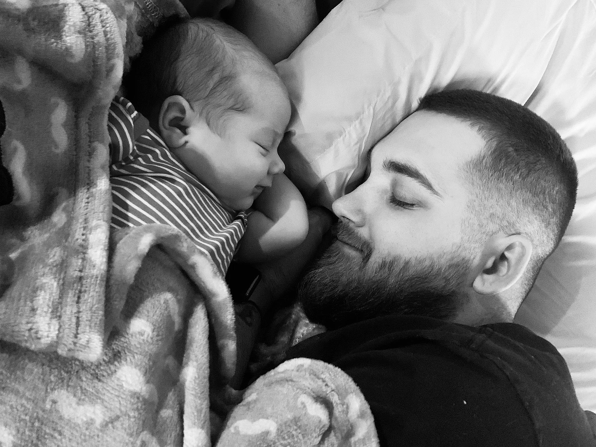 Micah is registered to the contest to win money with this photo: baby, baby_products, baby_toddler_clothing, beard, bedtime, cheek, child, comfort, ear, facial_hair, family, human, interaction, love, nap, people, person, skin, sleep, temple