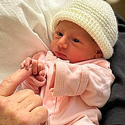 Gianna is registered to the contest to win money with this photo: newborn, baby, infant, hand, finger, knitted_hat, pink_clothing, sleepwear, person, skin, closeup, human, holding, cuddle, resting, cute, soft, warm, comfort, tenderness