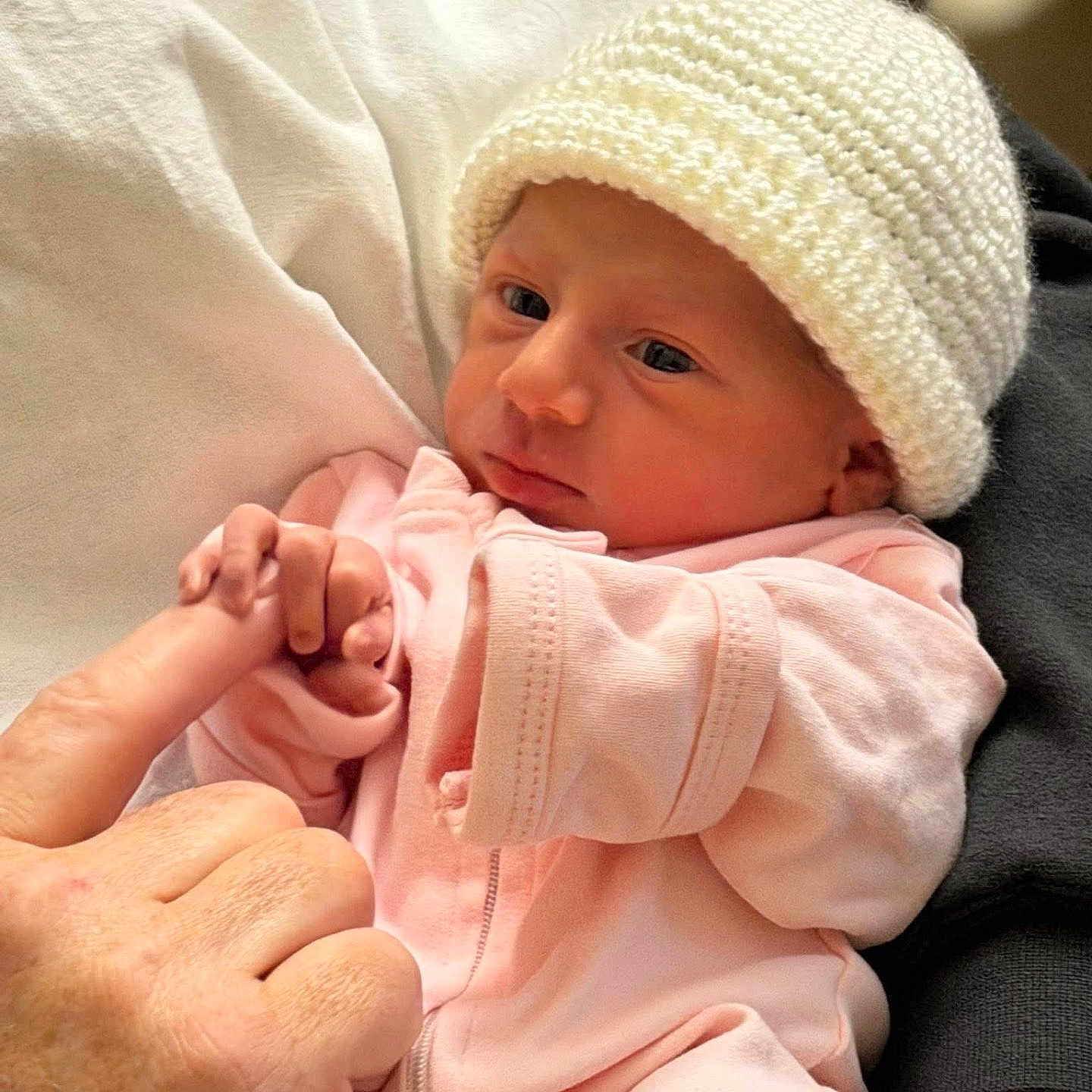 Gianna is registered to the contest to win money with this photo: newborn, baby, infant, hand, finger, knitted_hat, pink_clothing, sleepwear, person, skin, closeup, human, holding, cuddle, resting, cute, soft, warm, comfort, tenderness