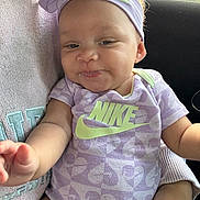 Harlowe is registered to the contest to win money with this photo: baby, infant, child, person, clothing, purple, headband, nike, onesie, smiling, arm, car_interior, seat, cute, face, hand, sitting, apparel, young, happy